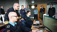 mehrere Männer in Uniform schauen auf einen Computer