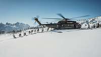 Ein großer Hubschrauber ist im verschneiten Gebirge gelandet. Zahlreiche Soldaten steigen aus.