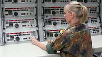 Eine Soldatin sitzt an komplexen Übertragungssystemen