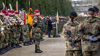 Vor einem Schloss im Hofgarten stehen zahlreiche Soldaten und Musiker in Formation.