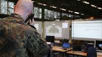 Ein Soldat telefoniert und schaut dabei auf mehrere Monitore.