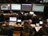 Mehrere Soldaten aus dem Zentrum für Cyber-Sicherheit der Bundeswehr arbeiten zusammen an Computern.