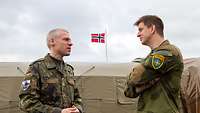 Ein deutscher und ein niederländischer Soldat besprechen sich vor einem Zelt.