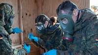 Drei Menschen mit Schutzmasken hantieren mit Laborgerät.