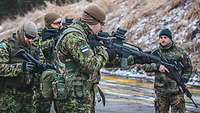 Drei estnische Luftwaffensoldaten lernen die Handhabung des G36, während ein deutscher Oberleutnant die Handhabung überwacht.