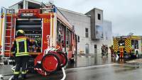 Ein Haus aus dem Rauch austritt, Feuerwehrleute beginnen die Brandbekämpfung
