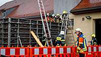 Feuerwehrleute an einer Verschalung auf einer Baustelle