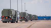 Die unterschiedlich großen Tankwagen der Bundeswehr fahren auf dem Hafengelände hintereinander zum Fähranleger