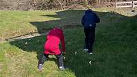Zwei Kinder suchen auf einer Wiese Ostereier