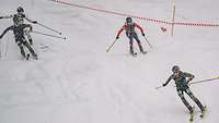 Vier Skifahrende kämpfen über eine unbefestigte Piste in einer Kurve um die beste Linie