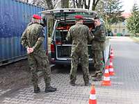 Mehrere Soldaten stehen vor einem Fahrzeug, dass den Kofferraum geöffnet hat.