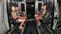 Five dummies are strapped in seated position in the cargo compartment of a helicopter.