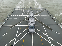A helicopter is standing on the landing pad of a large vessel. There are landing markings on the landing pad.