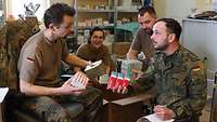 Drei Soldaten und eine Soldatin halten Medikamente in ihren Händen und begutachten sie.