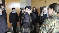 Mädchen stehen in einer Unterkunft und probieren Soldatenausrüstung an