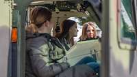 Drei Mädchen sitzen in einem Bundeswehrfahrzeug