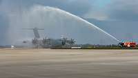 A400M auf Rollfeld unter Wasserfontäne der Flughafenfeuerwehr