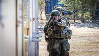 Drei Luftwaffensicherer gehen bewaffnet entlang eines Gebäudes