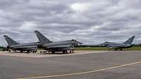 Zwei spanische Eurofighter und ein deutscher Eurofighter stehen in Estland auf dem Flugplatz