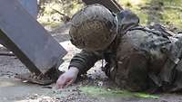 Ein Soldat liegt auf einem Boden, seine rechte Hand befindet sich in einer Pfütze