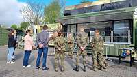 Eine Gruppe von Soldaten und Zivilisten steht vor einem Bundeswehrtruck