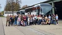 Eine Menschengruppe hat sich zu einem Gruppenbild vor zwei Bussen aufgestellt. 