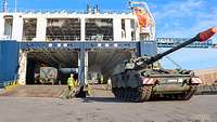 Eine Panzerhaubitze fährt auf ein Hafengelände. 