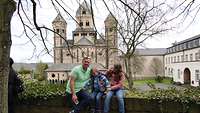 Menschen sitzen auf einer Mauer vor einer Kirche