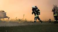 Zwei Feuerwehrleute löschen einen Brand.