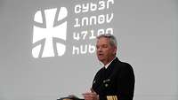 An admiral is speaking. Behind him are the words “Cyber Innovation Hub”.