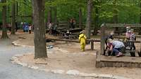 Kinder matschen und spielen am Wasserlauf aus Holz.