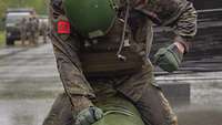 Ein auf dem Boden knieender Soldat in Flecktarn-Uniform schlägt auf einen Sandsack.