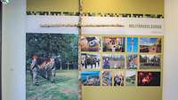 Infotafel mit Fotos zum Thema Militärseelsorge, davor ein Kreuz aus Birkenholz
