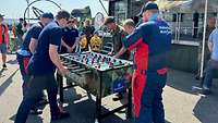 Vor dem Karrieretruck spielen Besucherinnen und Besucher am Kickertisch mit Bundeswehr-Angehörigen.