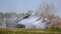 Four self-propelled howitzers firing on a field