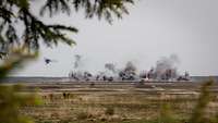 A large artillery target area in the distance with smoke rising.