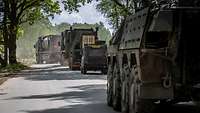 A convoy driving on a road enters difficult terrain.