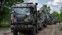 Three trucks with flatracks in the terrain