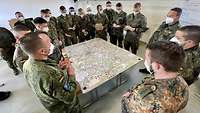 Several soldiers stand around a table with a situation map on top.