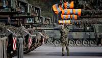 A soldier attaches barrel covers to the battle tanks.