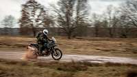 A motorcyclist races along a dirt road on his Enduro motorbike.