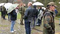 Menschen und zwei Soldaten stehen beieinander und reden.