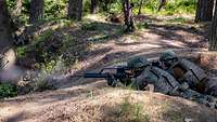 Zwei Soldaten liegen mit dem Gewehr im Wald in Stellung und schießen.