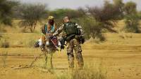 Ein deutscher Soldat auf Patrouille spricht mit einem malischen Einheimischen auf einem Esel