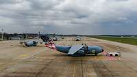 On an airfield there are transport planes, one of which is foiled with a US flag