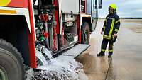 Ein Feuerwehrmann lässt Wasser aus einem Flugfeldlöschfahrzeug ab