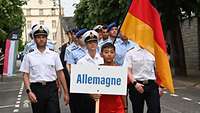 Soldatinnen und Soldaten laufen mit einem einheimischen Jugendlichen der das Deutschland-Schild trägt