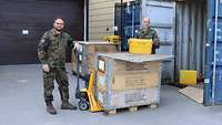 Das Feldpostteam steht neben einer großen Holzkiste mit Paketen.