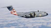 An A400M flies above the clouds. The fin is foiled with an American flag and the Statue of Liberty.