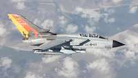 A tornado flies above the clouds. Air Defender is written on the fin.